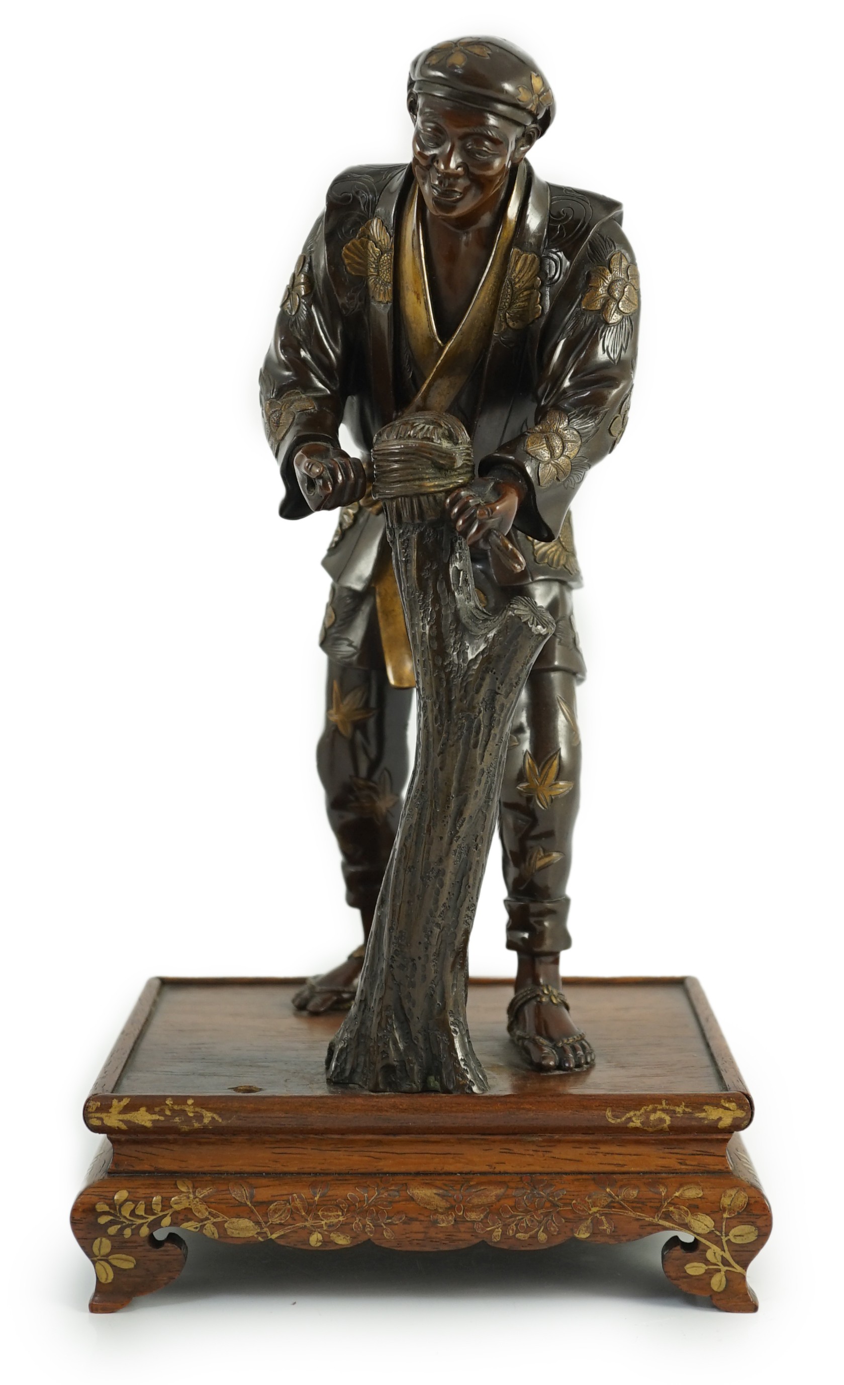 A Japanese brown patinated and gilded bronze figure of a woodworker, in Miyao style, Meiji period, 27.5cm high